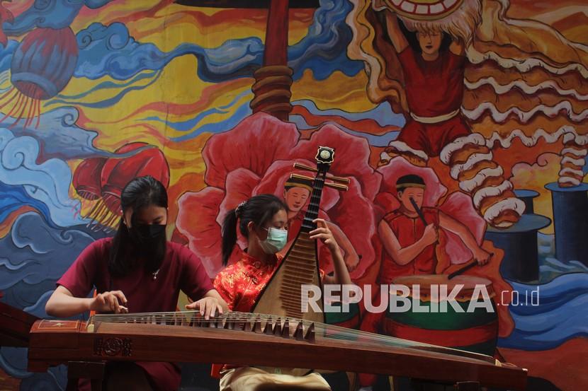 Dua remaja Tionghoa memainkan alat musik tradisional Tiongkok berupa Kecapi Guzheng dan Pipa saat menggelar pertunjukan di kawasan Gajahmada 9, Pontianak, Kalimantan Barat, Sabtu (12/2/2022). Pertunjukan alat musik tradisional Tiongkok dari Pecinan Pontianak Chinatown Indonesia (PPCI) tersebut digelar menjelang perayaan Cap Go Meh 2022 pada Selasa (15/2/2022) mendatang. 