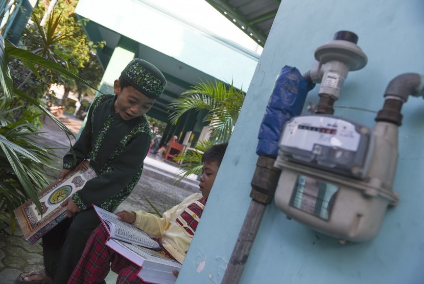 Dua santri bermain disamping meteran penyaluran gas bumi PGN di Tempat Pendidikan Alquran, Masjid Ummul Mu'minin, Surabaya, Jawa Timur, Selasa (19/7). 