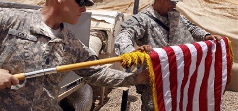 Dua serdadu AS tengah menggulung bendera kebanggaannya di kamp Minden, timur Bashra, Irak.