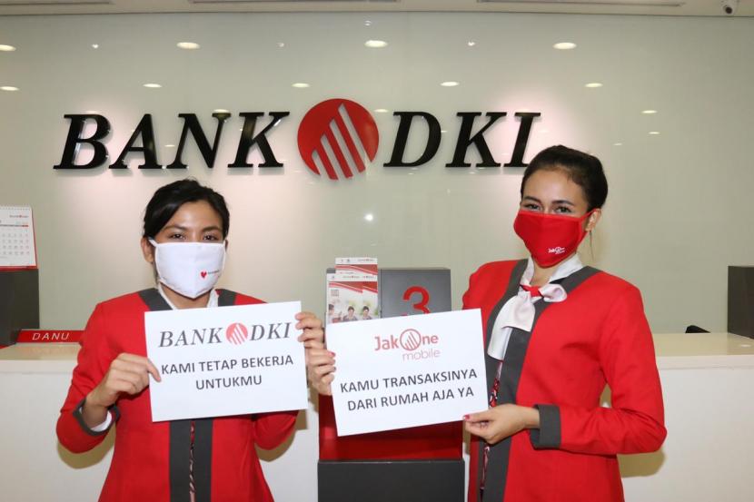 Dua staf Bank DKI tengah berfoto didepan banking hall salah satu kantor layanan di Jakarta (20/03). Meskipun tetap beroperasi Bank DKI menyarankan agar nasabah dapat melakukan transaksi dari rumah saja dengan menggunakan produk perbankan digital JakOne Mobile.