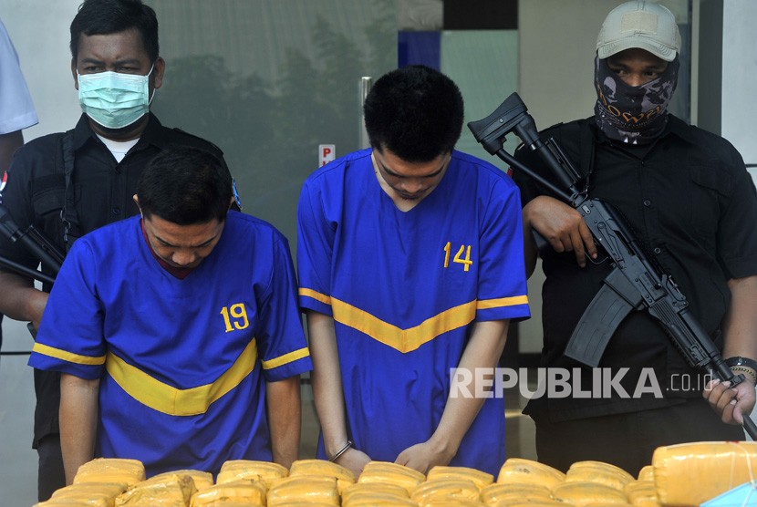 Dua tersangka sindikat narkoba FN (kiri) dan IG (kedua kiri) dijaga aparat BNN Banten saat acara pemusnahan 150 kilogram ganja di halaman Gedung BNN Banten, di Serang, Rabu (31/7/2019).