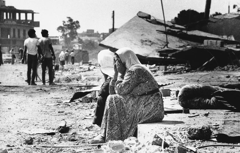 Dua wanita Palestina menangis saat mereka duduk di tepi jalan di kamp pengungsi Palestina Sabra di Beirut Barat, Lebanon, 19 September 1982, setelah mereka menemukan jenazah kerabat. (Foto AP / Bill Foley)