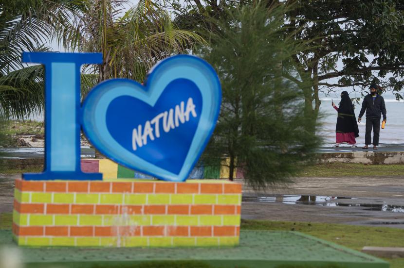 Dua warga berjalan di taman tepi Pantai Piwang, Ranai, Kabupaten Natuna, Kepulauan Riau, Sabtu (14/11/2020). Aktivitas perekonomian dan sosial masyarakat setempat berjalan normal dengan pemberlakukan protokol kesehatan khusus di tengah status zona kuning COVID-19 pada Natuna.