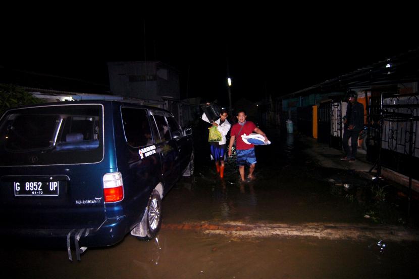 Dua warga membawa barang-barangnya saat akan mengungsi akibat rob (banjir pasang air laut) di Desa Dampyak, Kabupaten Tegal, Jawa Tengah, Rabu (3/6/2020) malam. Ratusan pemukiman warga di daerah tersebut terendam rob dengan ketinggian mencapai 50 sentimeter hingga satu meter dan sekitar 40 warga terpaksa mengungsi.