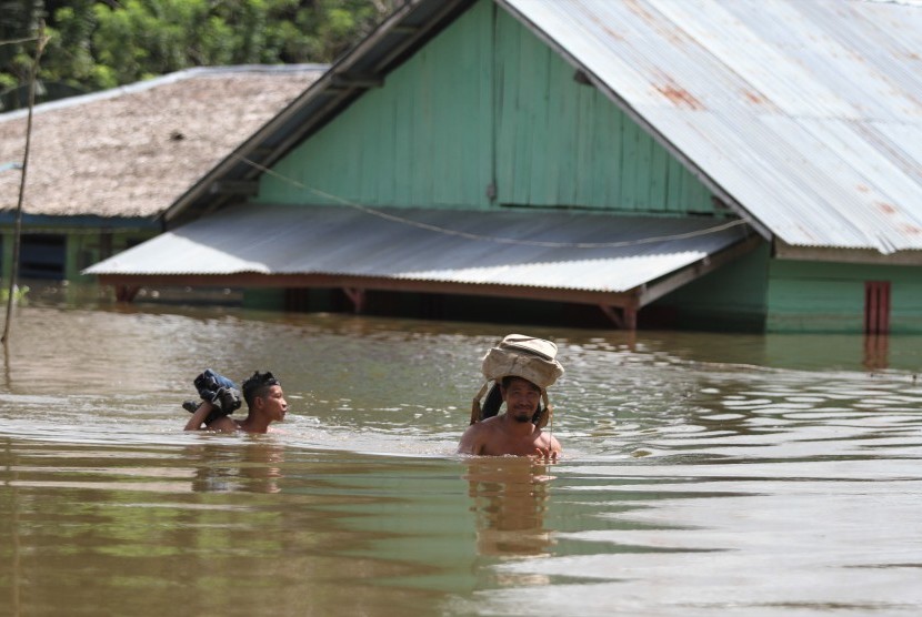 Dua warga menerobos banjir yang terjadi di Desa Tonduno, Konawe Selatan, Sulawesi Tenggara, Senin (17/6/2019). 
