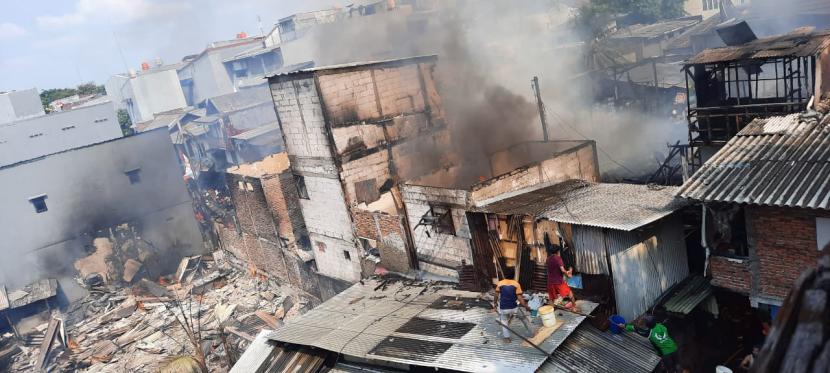 Dua warga sedang memadamkan api yang membakar sejumlah rumah di Jalan Indraloka V, Kelurahan Wijaya Kusuma, Grogol Petamburan, Jakarta Barat, Senin (9/8). 