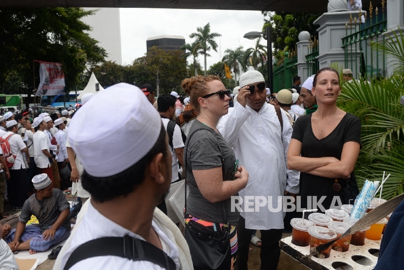 Dua wisatawan asing menonton Aksi Super Damai Bela Islam III di Monumen Nasional, Jakarta, Jumat (2/12).