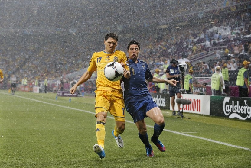 Duel antara Samir Nasri dan pemain Ukraina Taras Mikhalik di tengah hujan deras yang mengguyur stadion Donbass Arena