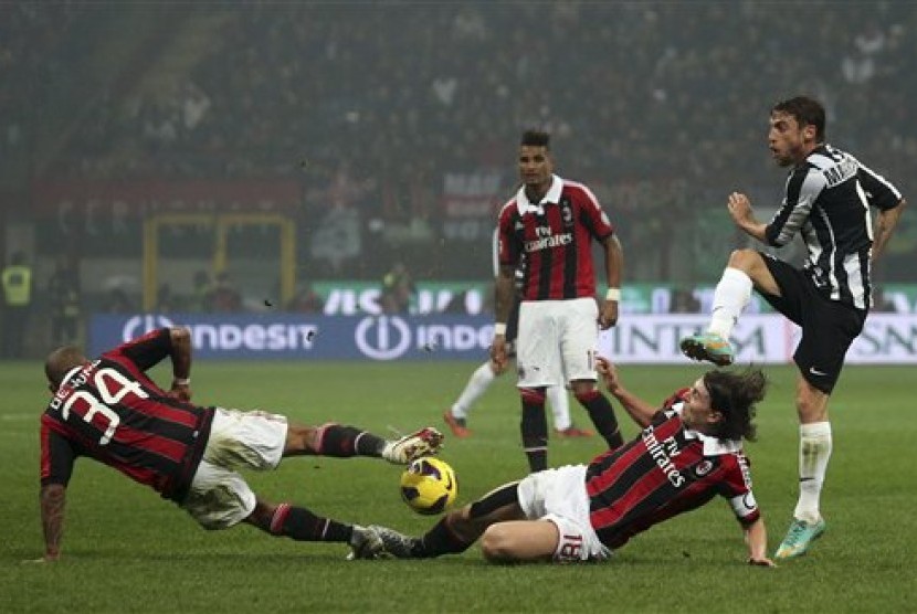 Duo gelandang AC Milan, Nigel De Jong, dan Riccardo Montolivo, berjibaku untuk menahan tendangan pemain Juventus, Claudio Marchisio. Pertandingan lanjutan Serie A yang berlangsung di San Siro, Senin (26/11) itu berhasil dimenangkan Milan 1-0.