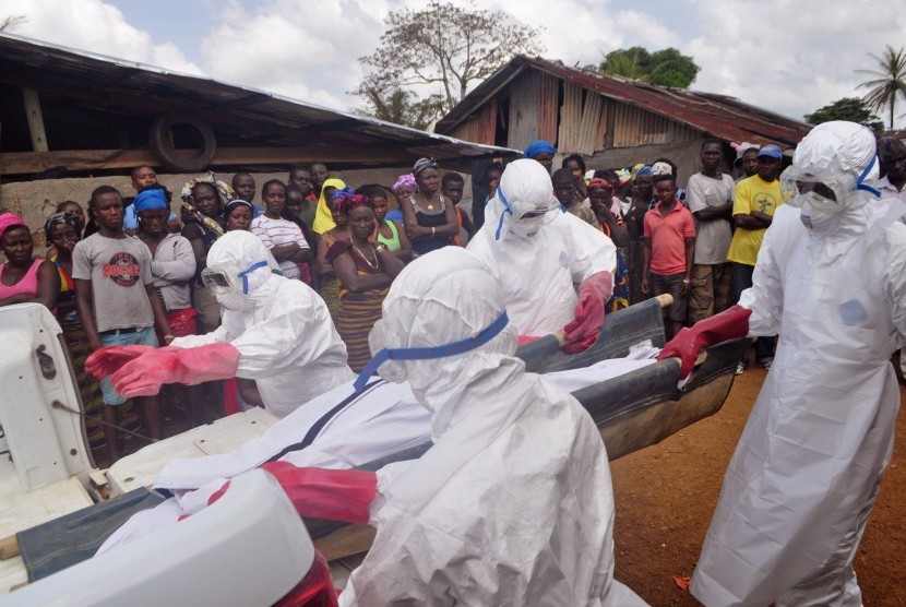 Ebola health care workers carry the body of a man suspected of dying from the Ebola virus in a small village Gbah on the outskirts of Monrovia, Liberia, Friday, Dec. 5, 2014.