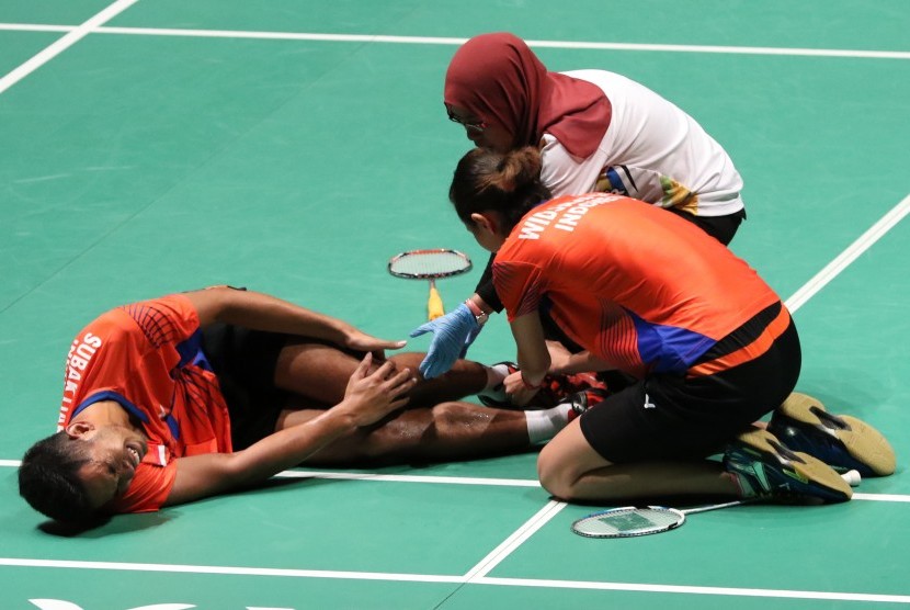 Edi Subaktiar (kiri) meringis kesakitan karena cedera dibantu pasangannya, Gloria Emmanuelle Widjaja (tengah) dan harus terhenti di babak pertama SEA Games 2017, Sabtu (26/8).