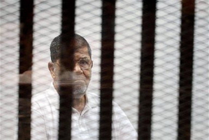 Egypt's ousted Islamist President Mohammed Morsi stands in a defendant cage in the Police Academy courthouse during a court hearing in Cairo, Egypt, Monday, Sept. 15, 2014. 