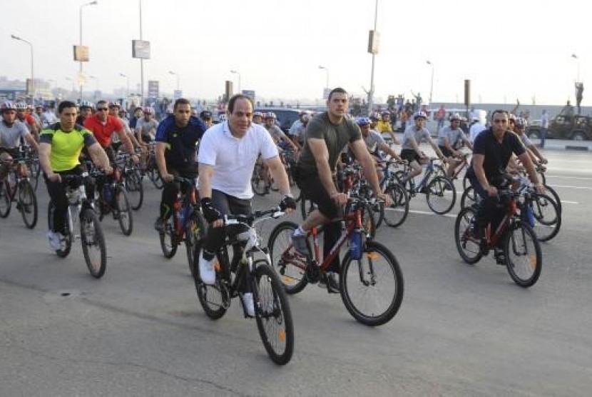 Egypt's President Abdel Fattah al-Sisi (front, white) rides a bicycle with few hundred Egyptians outside the military college in Cairo, June 13, 2014, in this handout picture provided by the Egyptian Presidency.