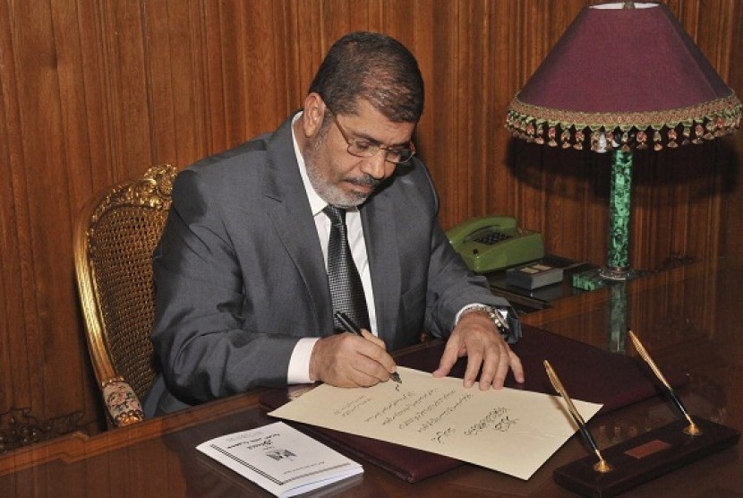 Egypt's President Mohamed Mursi signs a decree to put into effect the new constitution in Cairo December 25,   