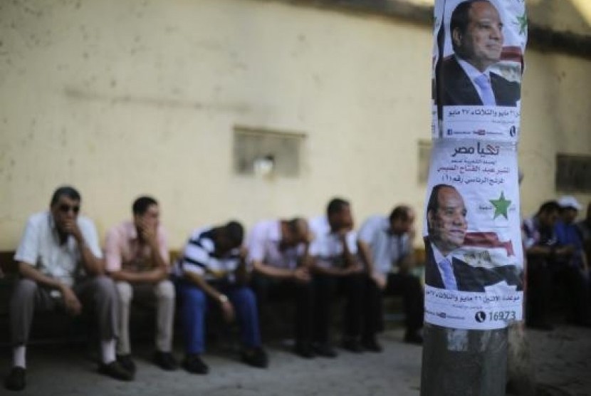 Egyptians sit on a bench near electoral posters of presidential candidate and former army chief Abdel Fattah al-Sisi near the Ittihadiya Palace in Cairo May 26, 2014.