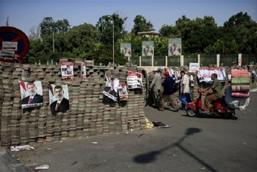 Egyptians walk between brick barricades erected along a street that leads to Rabaah al-Adawiya mosque. The supporters of Egypt's ousted President Mohammed Mursi have installed a camp and hold daily rallies at Nasr City, in Cairo, Egypt, Monday, July 29, 20