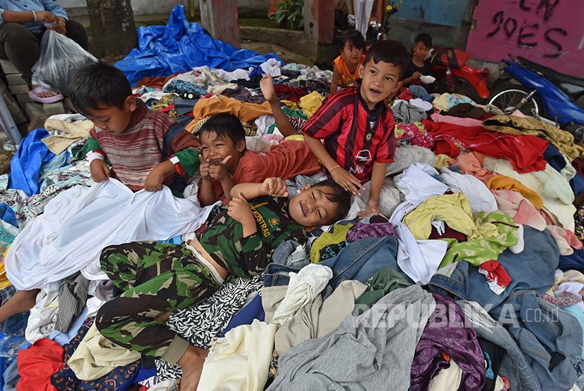 sejumlah anak korban banjir bandang Sungai Cimanuk bermain di atas baju sumbangan warga. 