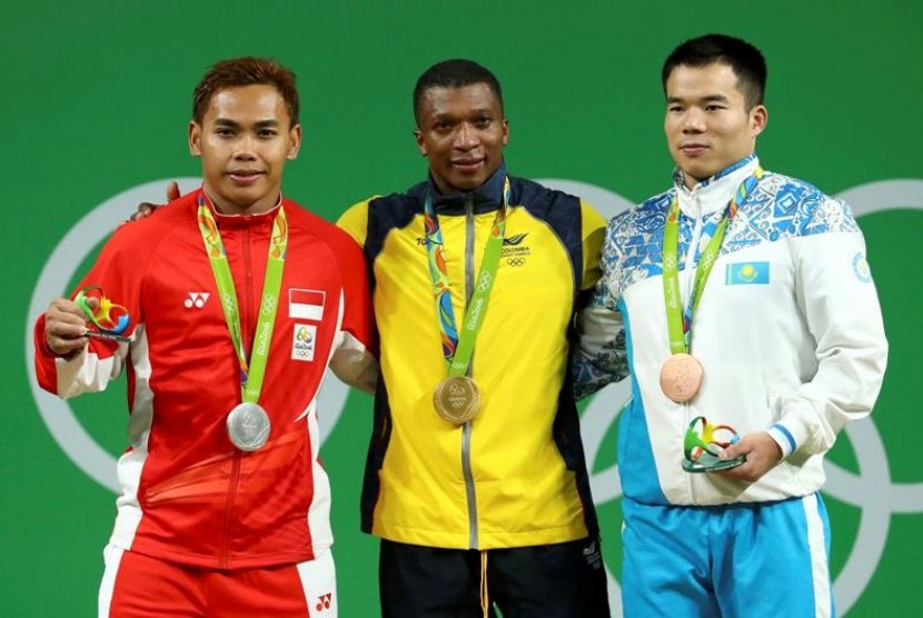 Eko Yuli Irawan (kiri) memegang medali perak yang diraihnya dari cabang angkat besi nomor 62 kg putra.