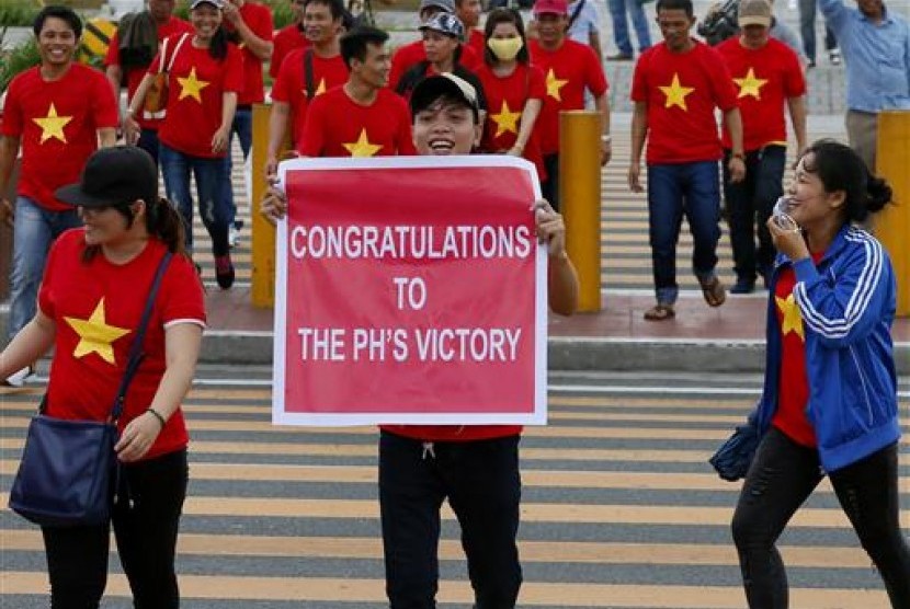 Ekspatriat Vietnam menyeberangi jalan sambil menunjukkan poster dukungan kepada Filipina sebelum keputusan pengadilan arbitrase internasional mengenai Laut Cina Selatan, Selasa, 12 Juli 2016. Vietna mendukung kasus Filipina ini.