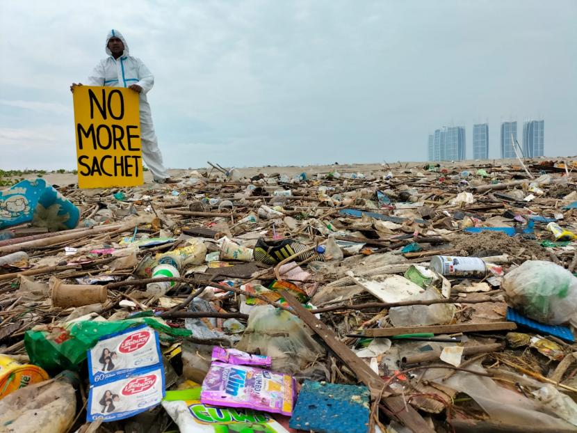 Empat aktivis pemerhati lingkungan berdiri di depan tumpukan sampah plastik di Pulau G di pantai utara Jakarta, Juni 2022. 