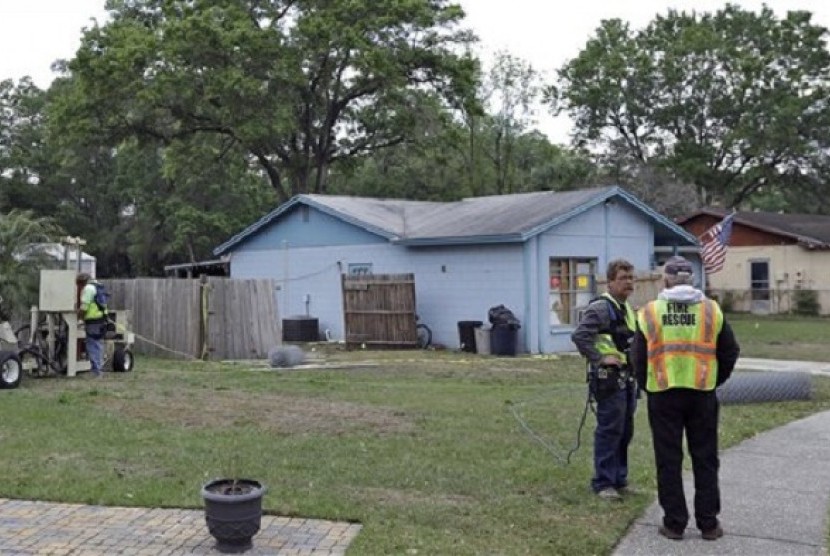 Engineers talk in front of a home where a sinkhole opened up underneath a bedroom late Thursday evening and swallowed a man in Seffner, Florida, US, on Saturday. 