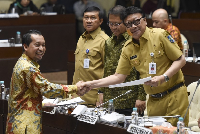 Menteri Dalam Negeri Tjahjo Kumolo (kanan) disaksikan Menteri Komunikasi dan Informatika Rudiantara (kiri) menerima pandangan mini fraksi dari anggota Komisi II fraksi PKS Sutriyono (kiri) saat rapat kerja dengan Komisi II DPR di Kompleks Parlemen, Senayan, Jakarta, Senin (23/10). Pada hari ini, DPR menggelar Sidang Paripurna pengambilan keputusan Perppu Ormas.