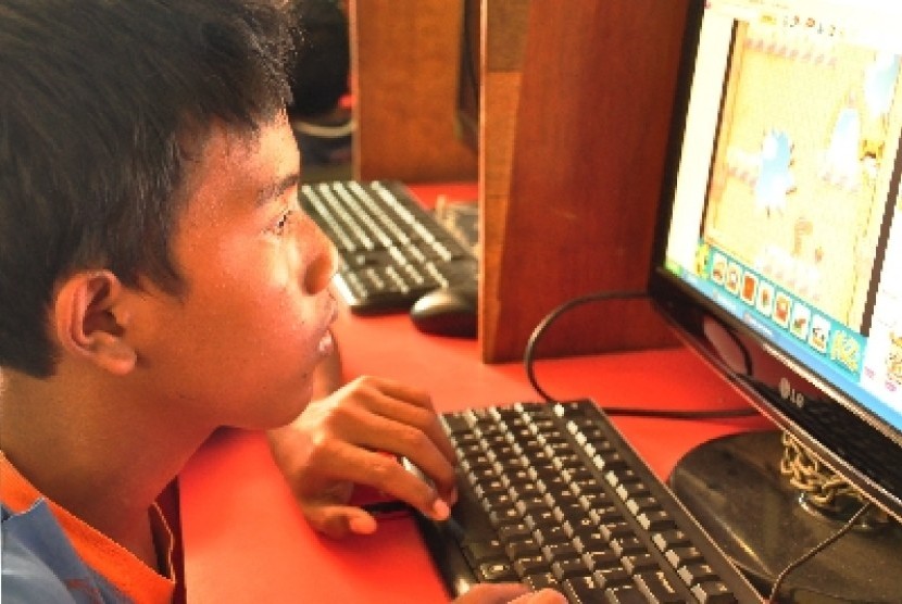 Seorang anak bermain game online di warnet