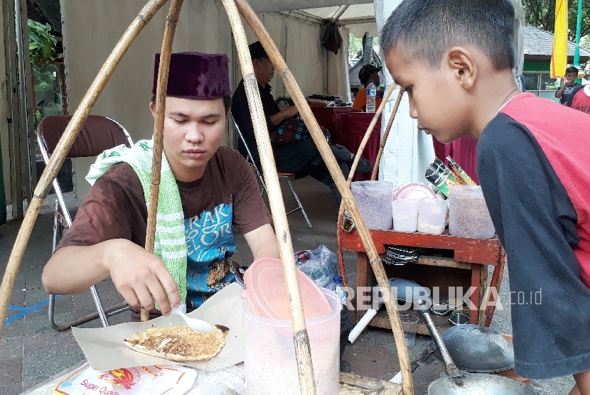 eorang anak membeli kerak telor di booth kerak telor pada acara pentas seni budaya dan kuliner betawi di Taman Impian Jaya Ancol Jakarta, Ahad (15/10). 