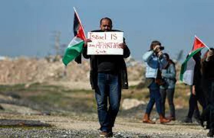 eorang pengunjuk rasa membawa tanda selama demonstrasi oleh pengunjuk rasa Palestina, Israel, dan asing menentang Rute 4370 yang baru dibuka, di Tepi Barat, pada 23 Januari 2019. 