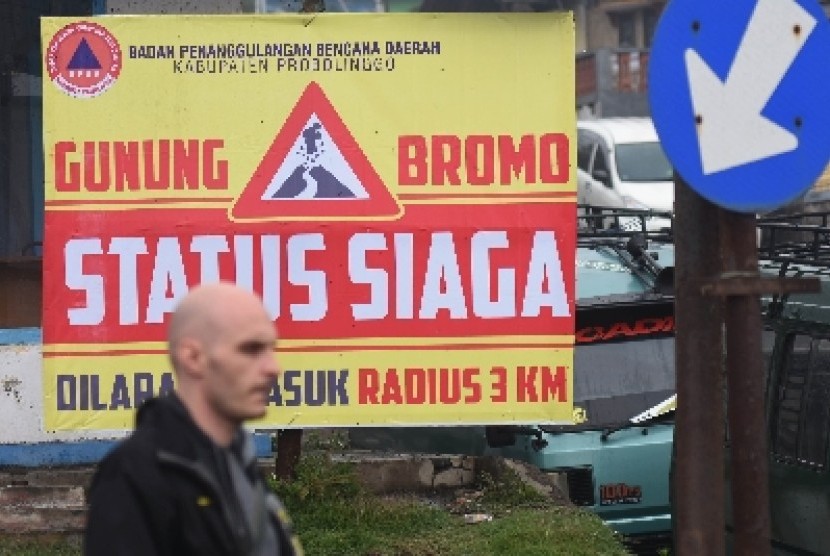 eorang wisatawan mancanegara melintas didepan papan peringatan status siaga Gunung Bromo di Cemoro Lawang, Probolinggo, Jawa Timur, Minggu (6/12). Akibat meningkatnya aktivitas gempa tremornya semakin tinggi, pihak Taman Nasional Bromo Tengger Semeru (TNBT