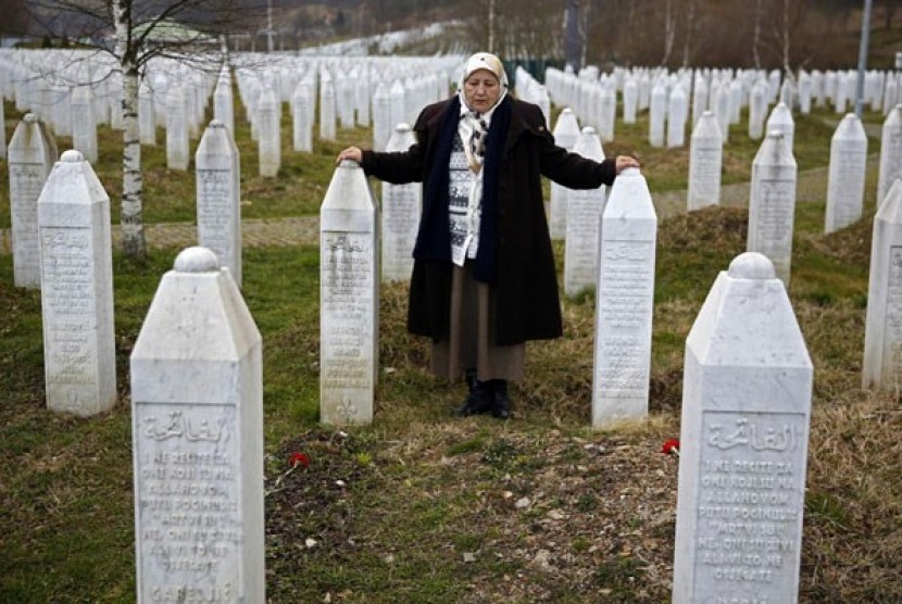 Fadila Efendic meletakkan tangannya di atas pusara putranya dan suaminya di pusat memorial genosida Potocari dekat Srebenica, Bosnia Herzegovina 