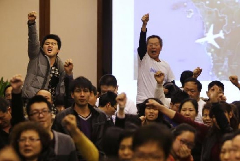 Family members of passengers onboard Malaysia Airlines Flight MH370 raise their fists as they shout ''return our families'' after a routine briefing given by Malaysia's government and military representatives in Beijing March 22, 2014.