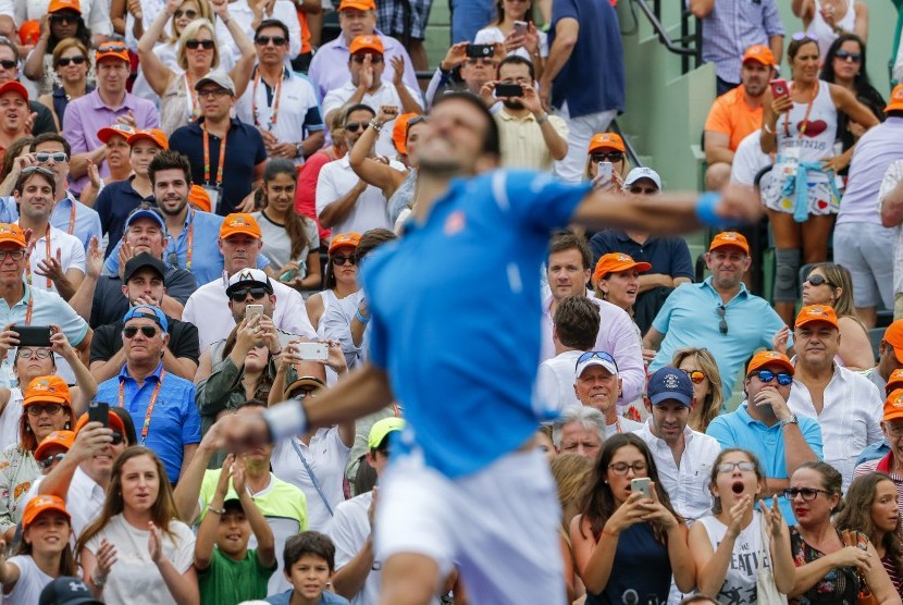Fan menyaksikan petenis Serbia, Novak Djokovic, melakukan selebrasi usai mengalahkan petenis Jepang, Kei Nishikori, dalam laga final Miami Terbuka di Key Biscayne, Miami, Florida, Amerika Serikat, Sabtu (3/4). 