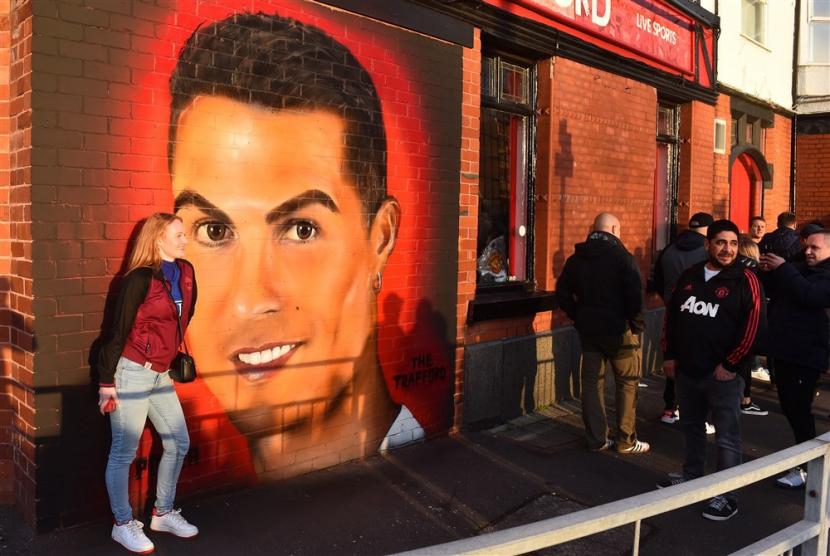  Fan berjalan melewati mural Cristiano Ronaldo di dinding pub di luar Stadion Old Trafford di Kota Manchester, Inggris, belum lama ini.
