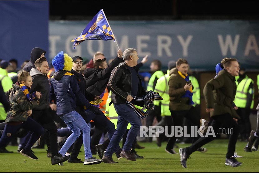 Fan Shrewsbury Town menyerbu lapangan usai laga melawan Liverpool di Montgomery Waters Meadow, Shrewsbury, Inggris, Senin (27/1) dini hari. 