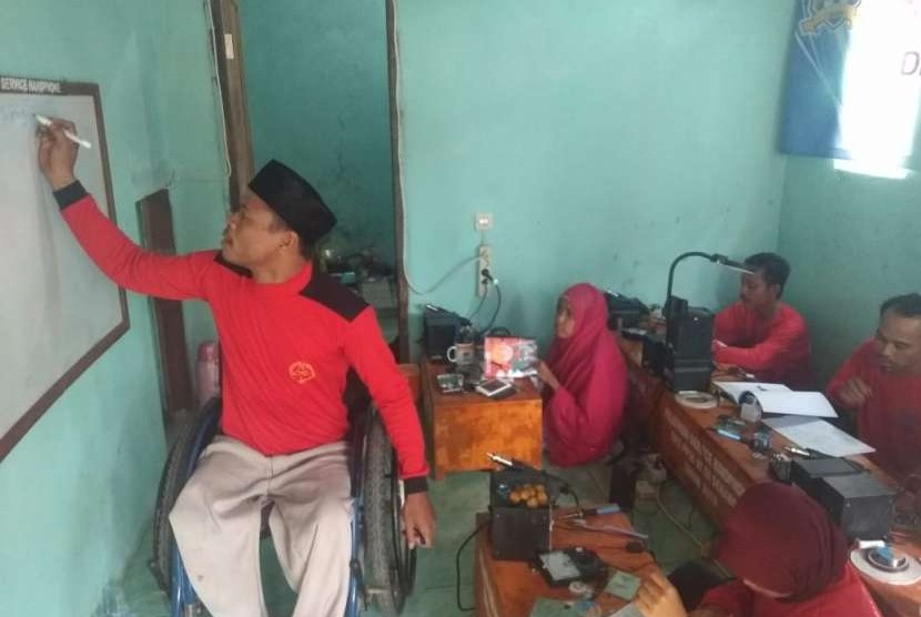 Ferdy Syamsuddin memberikan pelatihan memperbaki telepon genggam ke penyandang disabilitas yang lain.