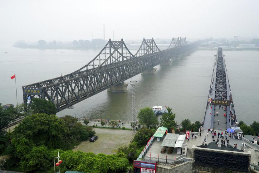 FILE - Dalam foto arsip 9 September 2017 ini, pengunjung berjalan melintasi Jembatan Rusak Sungai Yalu, kanan, di sebelah Jembatan Persahabatan yang menghubungkan China dan Korea Utara di Dandong di provinsi Liaoning, China timur laut.