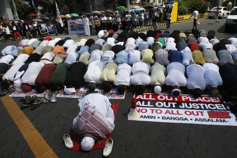 Filipino Muslims hold their Friday prayers near the Presidential Palace as Christians wait for their turn in the background during a 