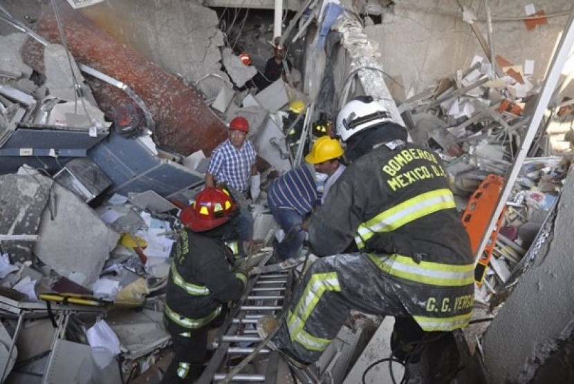 Firefighters belonging to the Tacubaya sector and workers dig for survivors after an explosion at a building adjacent to the executive tower of Mexico's state-owned oil company PEMEX, in Mexico City, Thursday Jan. 31, 2013. 