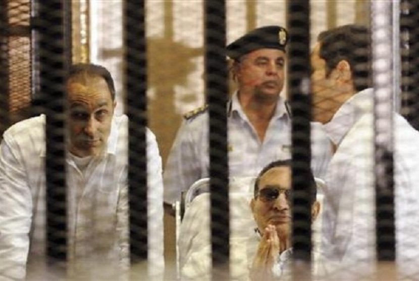 Former Egyptian president Hosni Mubarak (center) sits with his sons Gamal (left) and Alaa (right) inside a cage in a courtroom at the police academy in Cairo April 13, 2013. 