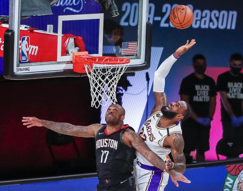 Forward Los Angeles Lakers LeBron James (kanan) berusaha memasukkan bola saat melawan Houston Rockets dalam pertandingan ketiga play-off semifinal Wilayah Barat NBA.