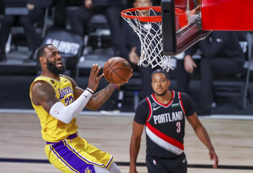 Forward Los Angeles Lakers LeBron James (kiri) memasukkan bola saat melawan Portland Trail Blazers dalam laga kelima putaran pertama play-off NBA di ESPN Wide World of Sports Complex, Kissimmee, Florida, AS, Ahad (30/8) WIB.