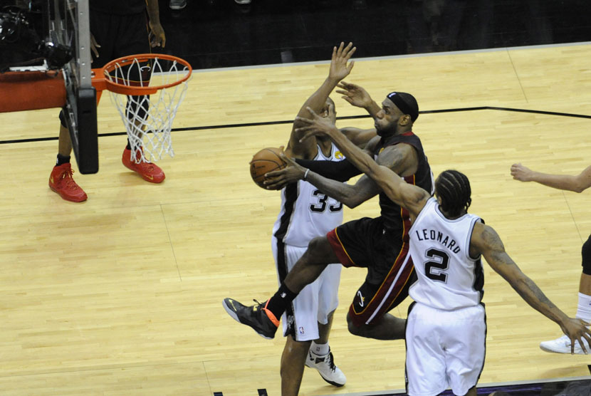 Forward Miami Heat, Lebron James (tengah), mencoba menjaringkan bola di tengah kepungan pemain San Antonio Spurs di laga final NBA 2014. 