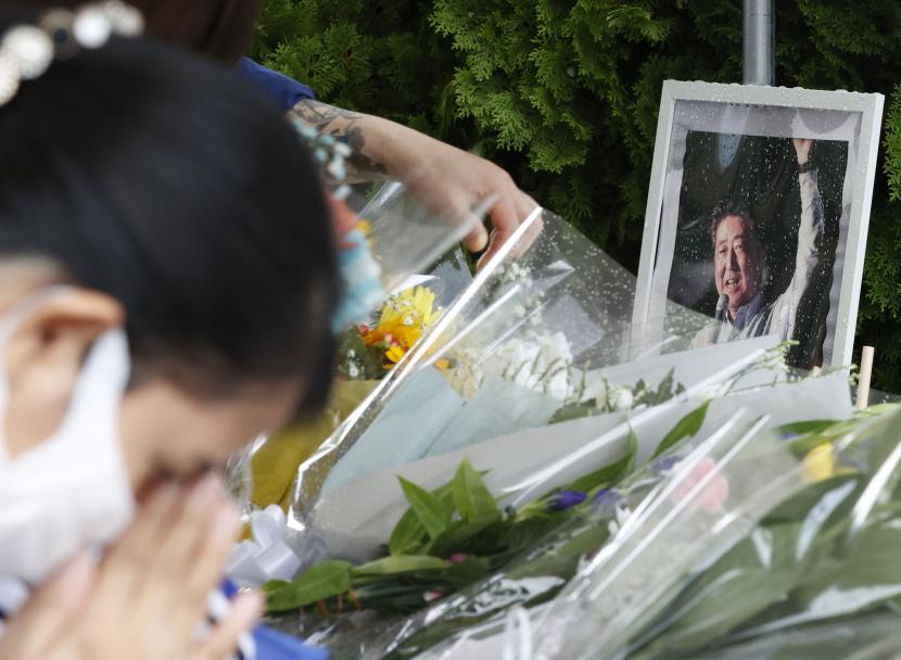  Foto mantan Perdana Menteri Shinzo Abe dipajang di tugu peringatan darurat di dekat lokasi di mana Abe tertembak hingga tewas saat menyampaikan pidato mendukung calon Partai Demokrat Liberal pada Jumat, di Nara, Sabtu, 9 Juli 2022. 
