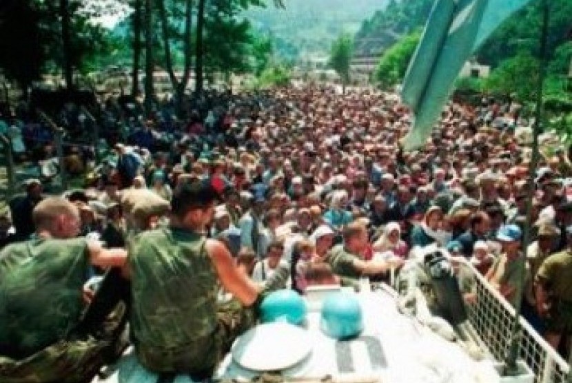 Foto pada 13 Juli 1995, tampak dua tentara Pasukan PBB asal Belanda duduk di atas APC melihat warga Muslim Srebenica berkumpul di desa Potomari sebelum digiring oleh tentara Serbia.