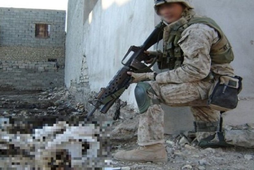 Foto seorang tentara Amerika Serikat sedang mengacungkan senjata ke jenazah pejuang Irak.