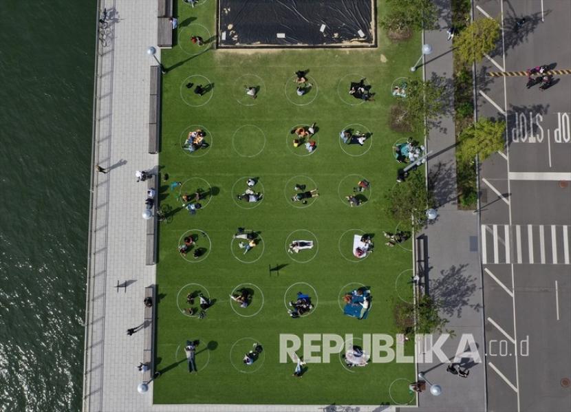 Foto udara memperlihatkan warga New York menghabiskan waktu dalam lingkaran putih yang dilukis di atas rumput untuk membantu para pengunjung taman tetap terpisah sejauh 6 kaki sebagai tindakan pencegahan terhadap pandemi virus korona (Covid-19) di Domino Park di Williamsburg pada 19 Mei 2020 di New York City, Amerika Serikat.