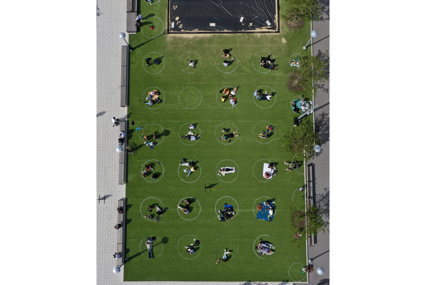 Foto udara memperlihatkan warga New York menghabiskan waktu dalam lingkaran putih yang dilukis di atas rumput untuk membantu para pengunjung taman tetap terpisah sejauh 6 kaki sebagai tindakan pencegahan terhadap pandemi virus korona (Covid-19) di Domino Park di Williamsburg pada 19 Mei 2020 di New York City, Amerika Serikat.