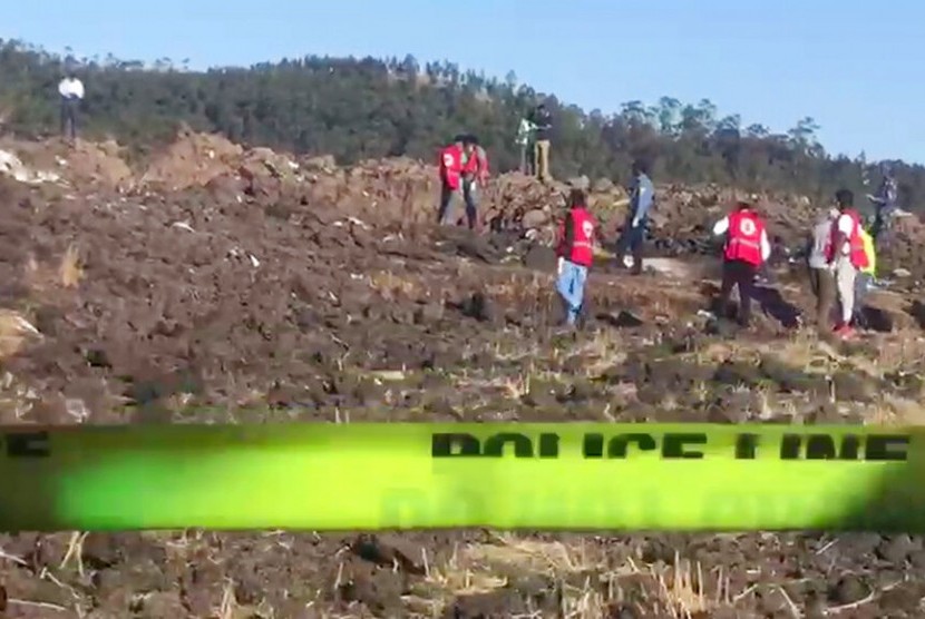 Foto yang diambil dari video menunjukkan, petugas mencari korban di antara puing-puing jatuhnya pesawat Ethiopian Airlines di daerah Hejere, sekitar 50 km dari selatan Addis Ababa, Kenya, Ahad (10/3).