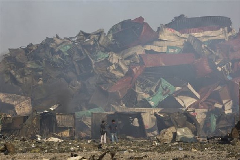 Fotografer berada di dekat sisa-sisa peti kemas yang hancur akibat ledakan di sebuah gudang di Kota Tianjin, Kamis (13/8). 